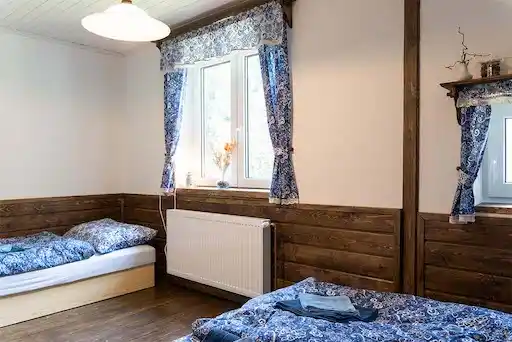krásná ložnice v patře s přiznaným trámem, postelí a výhledem do zahrady