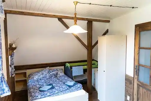krásná ložnice v patře s přiznaným trámem, dětskou postýlkou a manželskou postelí