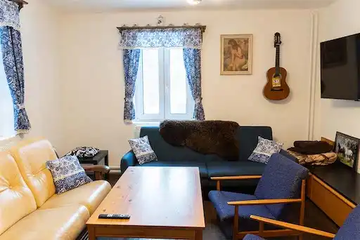 Obývací pokoj s pohodlným posezením, smart televizí a kytarou pověšenou na zdi